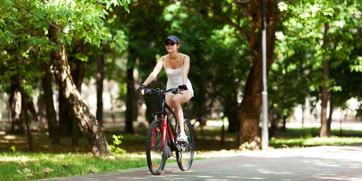 kobieta jadąca przez park na rowerze